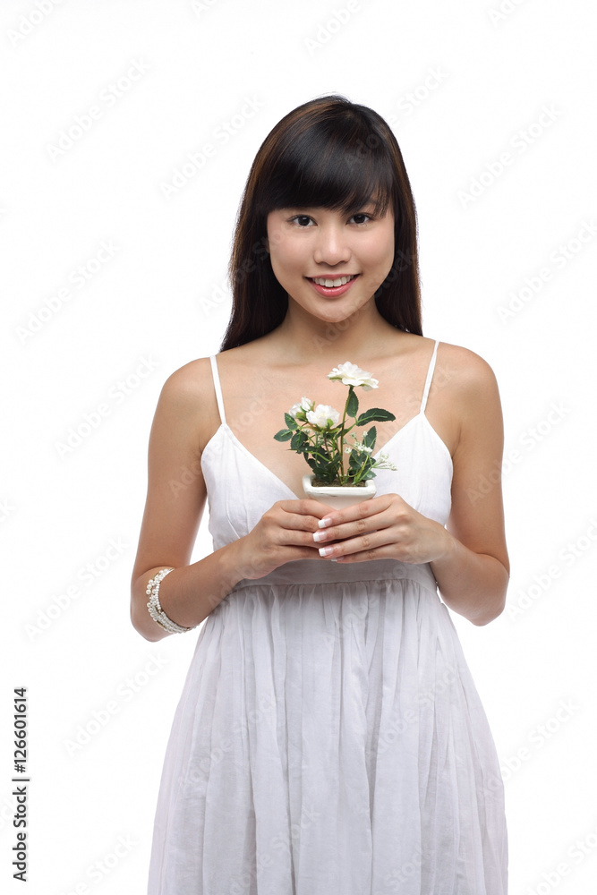 Young woman wearing white dress and holing small plant Young woman wearing white dress and holing small plant