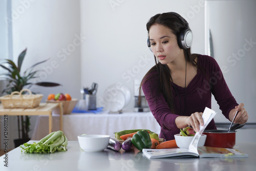 Young woman cooking while listening to music