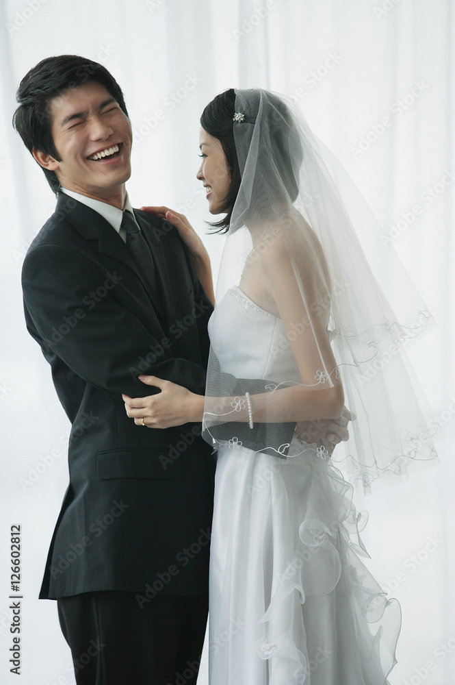 A newlywed couple stand with their arms around each other A newlywed couple stand with their arms around each other