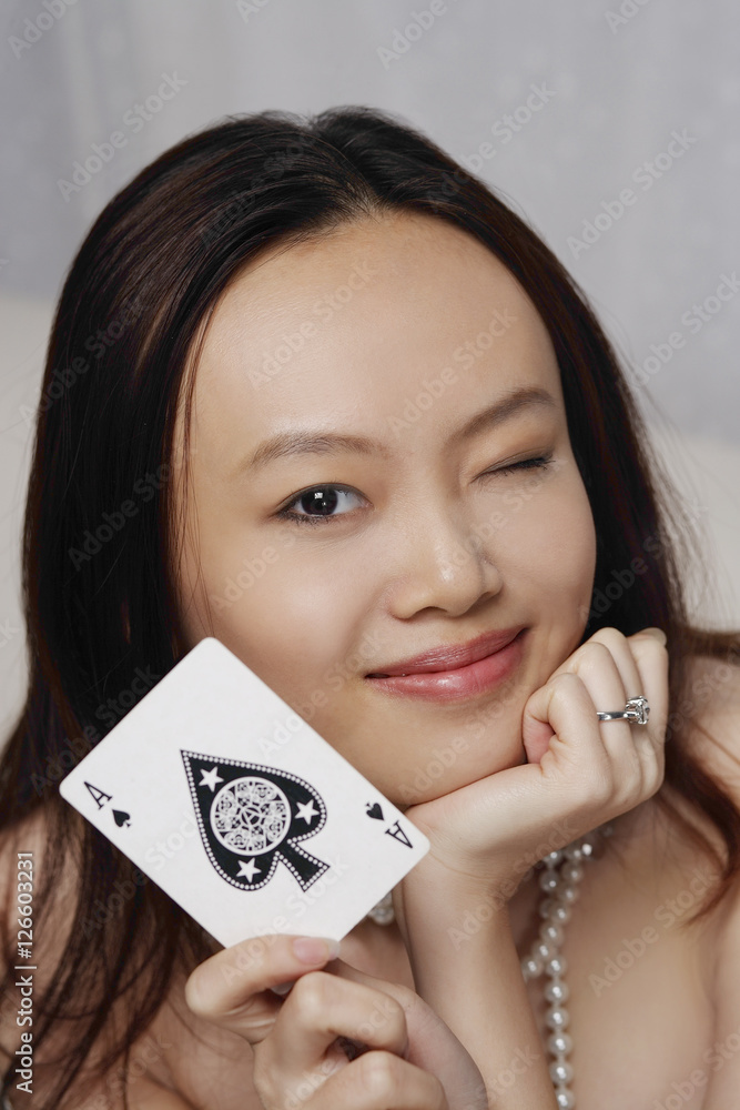 Young woman holding ace of spades card