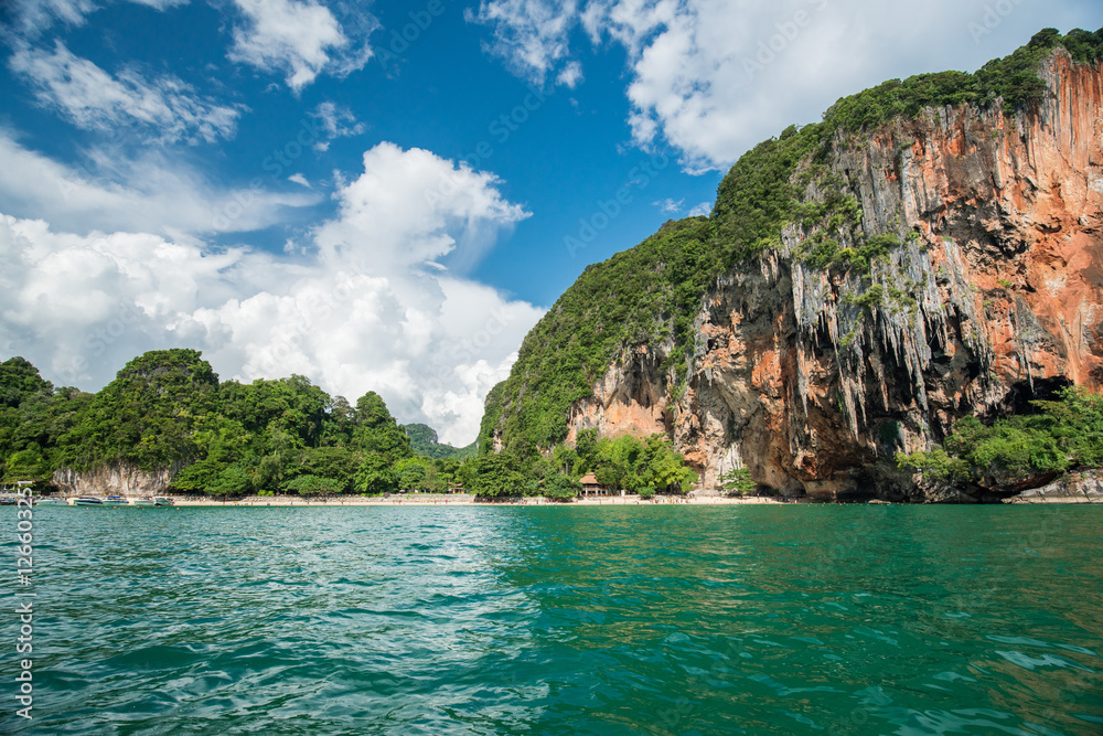 Tropical landscape with rock islands, lonely boat and crystal cl Tropical landscape with rock islands, lonely boat and crystal cl