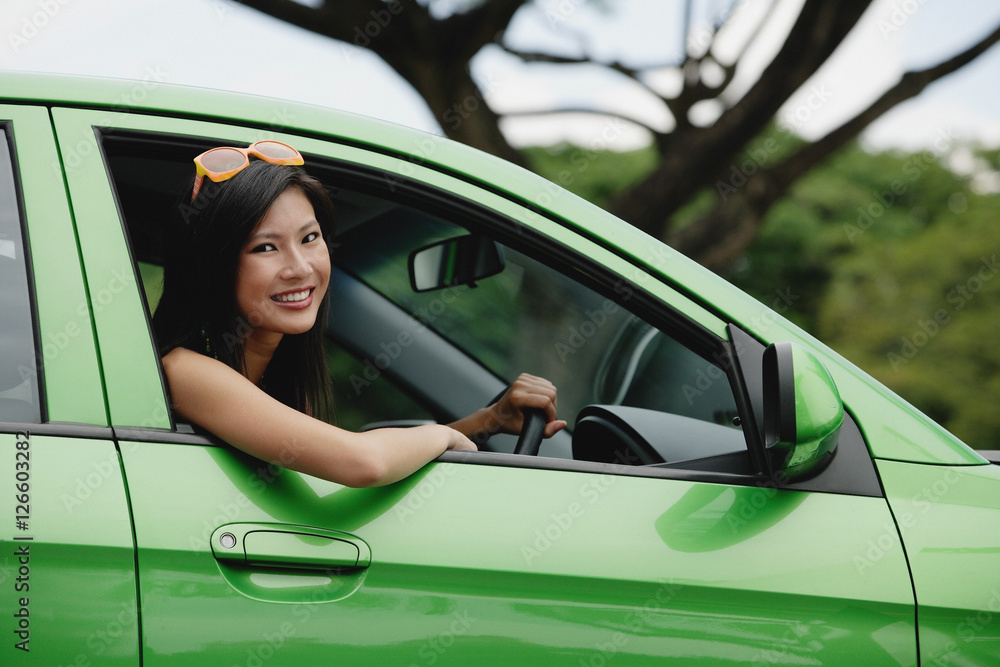 A young woman drives a green car