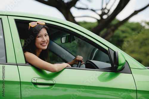 Obraz na płótnie A young woman drives a green car w salonie