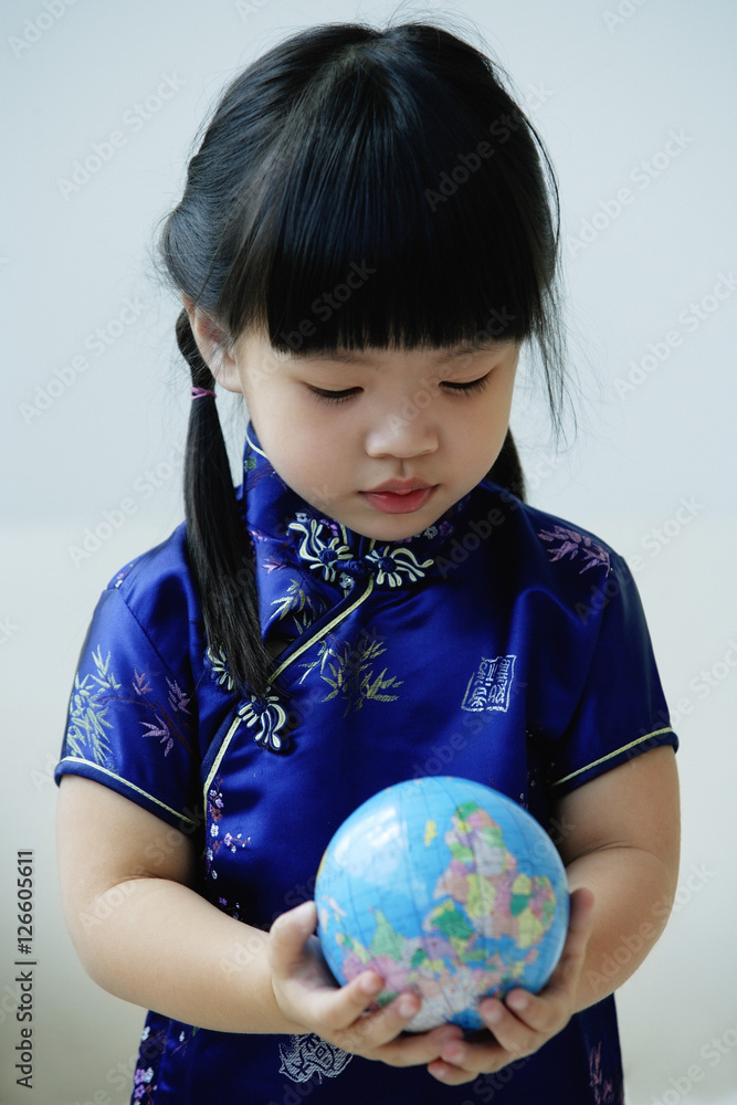A small girl in blue silk cheongsam holds a globe A small girl in blue silk cheongsam holds a globe