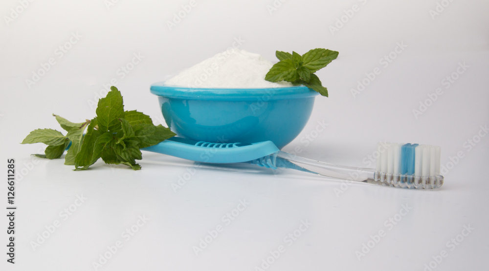 Baking Soda in a Turquoise Bowl, Fresh Mint and Toothbrush Used to Whitening Teeth and Freshen Breath against a White Background Baking Soda in a Turquoise Bowl, Fresh Mint and Toothbrush Used to Whitening Teeth and Freshen Breath against a White Background