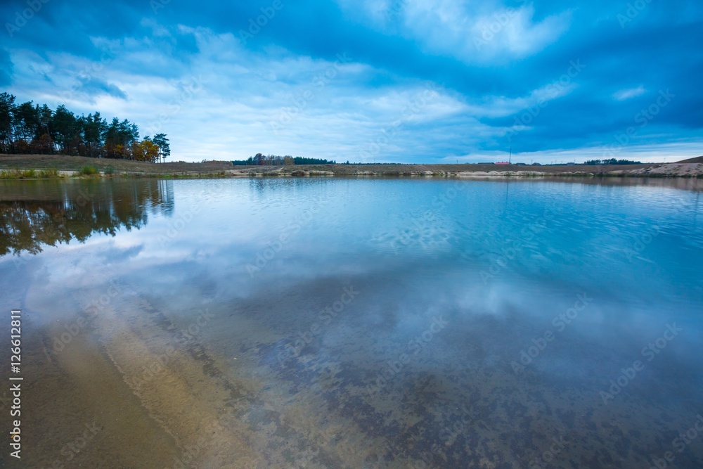 Small lake under dark cloudy sky