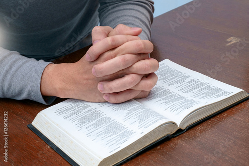 Male hand on the Bible, praying to God.