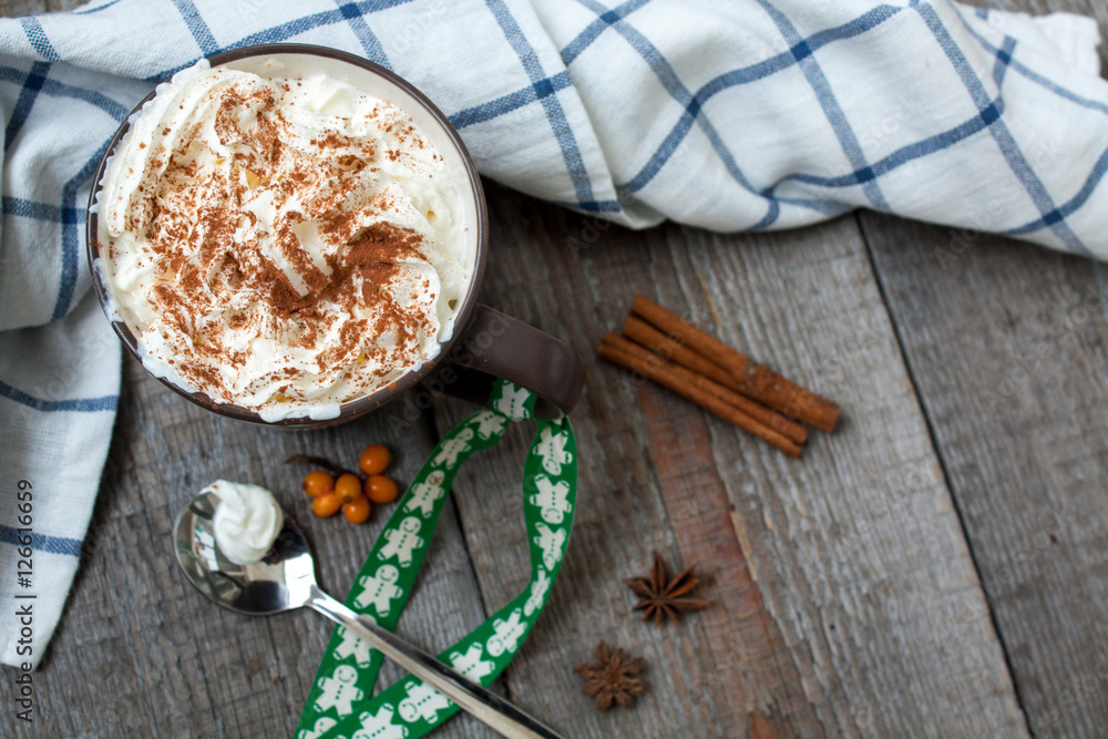 Christmas drink with whipped cream, decorated with a ribbon with a gingerbread man. hot chocolate or cocoa with chocolate, cinnamon, berries. Christmas drink with whipped cream, decorated with a ribbon with a gingerbread man. hot chocolate or cocoa with chocolate, cinnamon, berries.