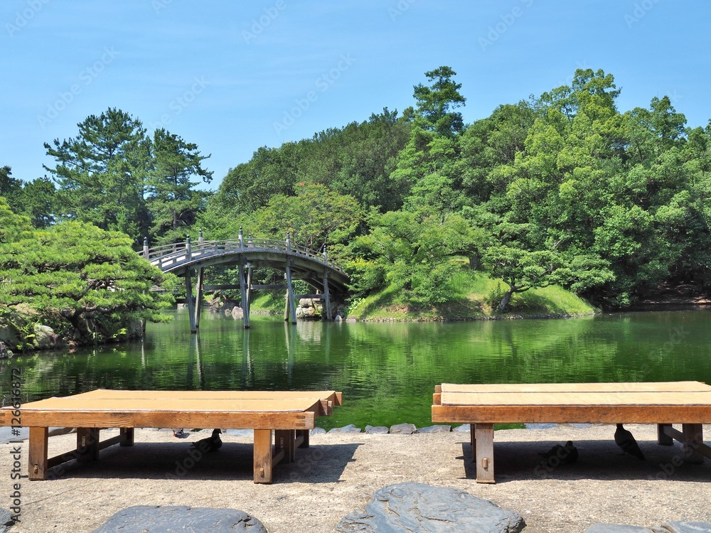 Wooden benches and wooden bridge - Engetsukyo in Ritsurin Garden in Takamatsu city, Kagawa Prefecture, Japan. Ritsurin Garden is one of the most famous historical gardens in Japan.
