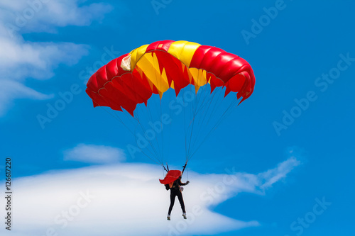 Skydiver and colorful parachute on blue sky background