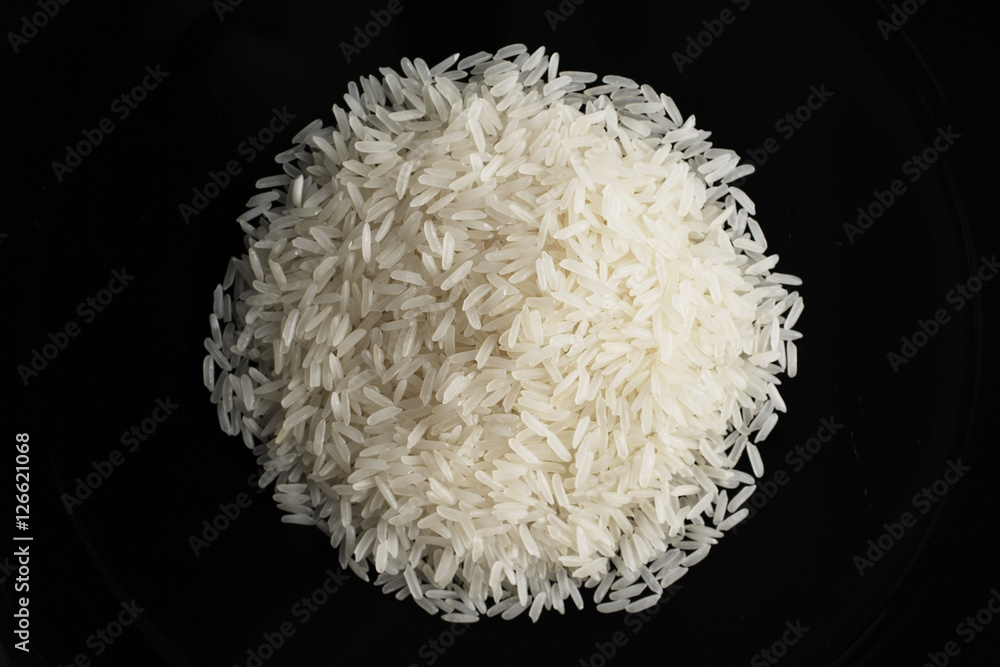 a pile of uncooked rice against a black plate a pile of uncooked rice against a black plate