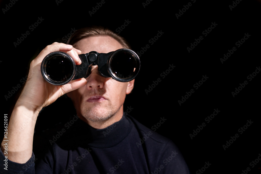 man looking through binoculars on a dark background man looking through binoculars on a dark background