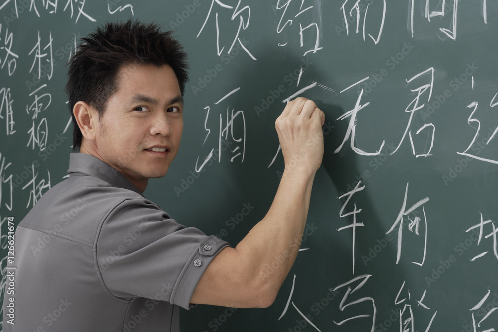 man writing Chinese characters on chalk board man writing Chinese characters on chalk board