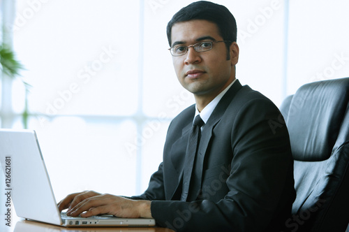 Businessman in office, sitting at desk, looking at camera