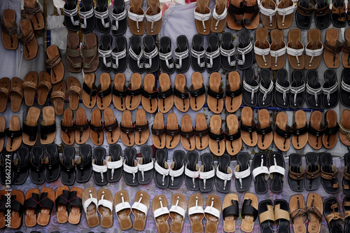 Many leather sandals on display at market.