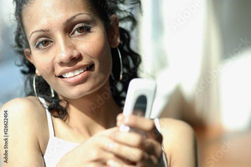 Woman holding mobile phone, looking at camera