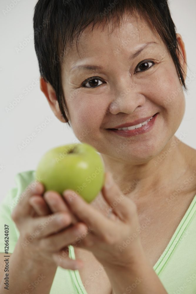 Mature Chinese woman holding green apple and smiling Mature Chinese woman holding green apple and smiling