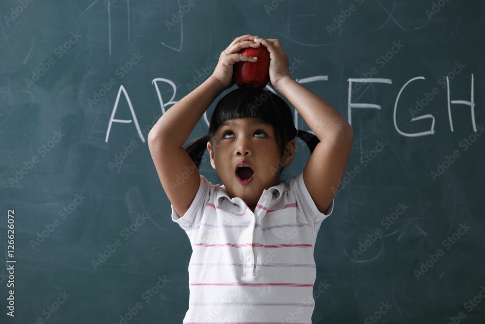 Young girl holding apple on top of her head