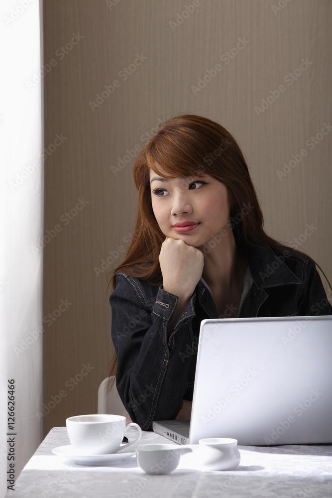 Young woman sitting at table with laptop Young woman sitting at table with laptop