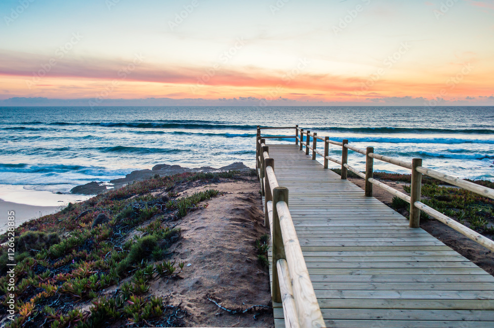 Wooden walkway on the Atlantic ocean coast in the sunset time in Alentejo, Portugal