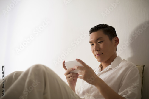 Canvas Print Singapore, Young man texting on sofa