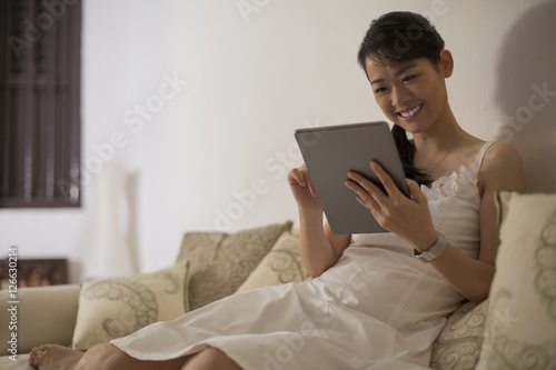 Singapore, Woman sitting on sofa using digital tablet