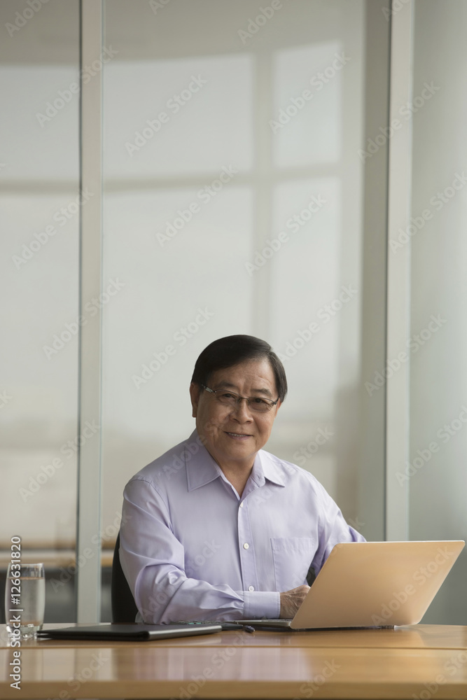 Singapore, Senior businessman using laptop at desk