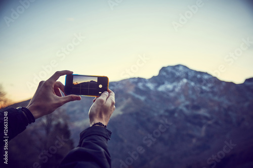 Ragazzo scatta foto in montagna con smartphone © CreativePhotography