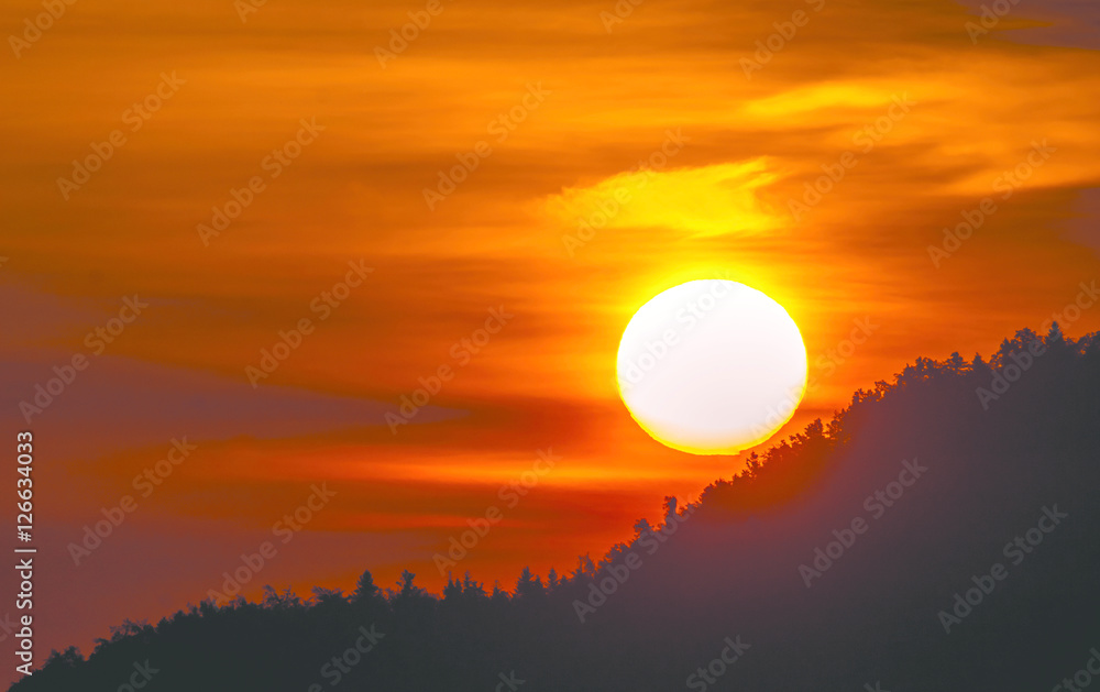 Sun and silhouette of mountains with fog