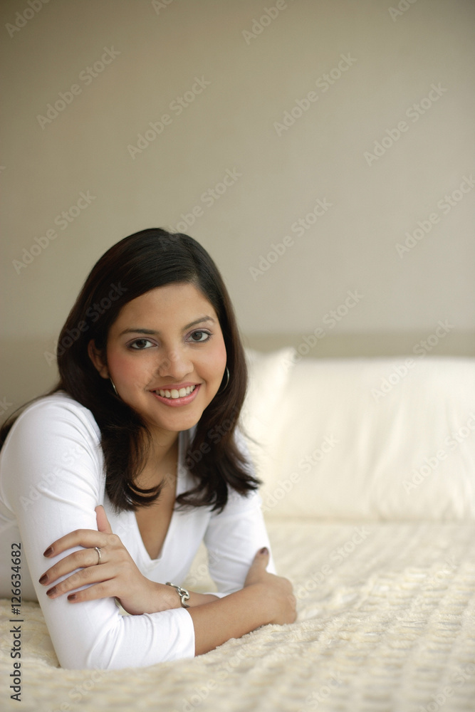 Woman lying on bed, arms crossed, smiling Woman lying on bed, arms crossed, smiling