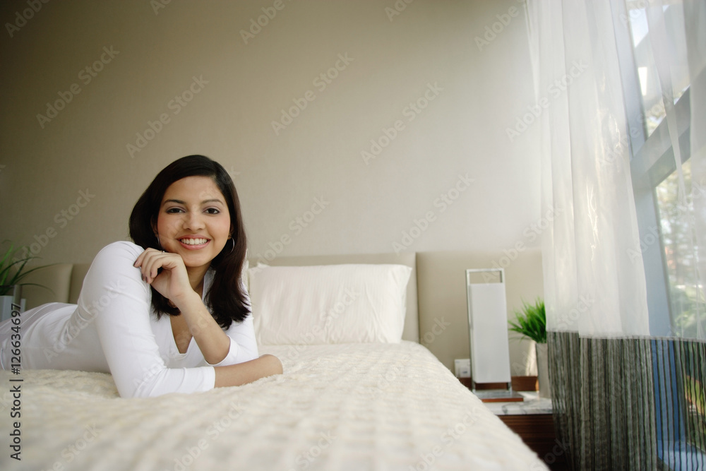 Woman lying on bed smiling at camera Woman lying on bed smiling at camera