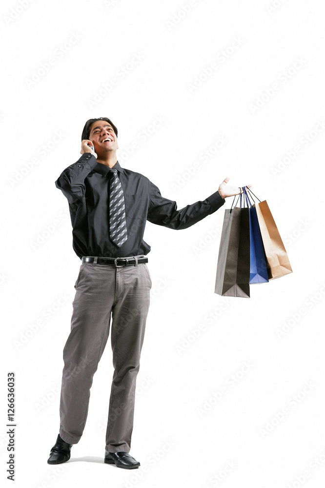 Businessman talking on mobile phone, carrying shopping bags Businessman talking on mobile phone, carrying shopping bags