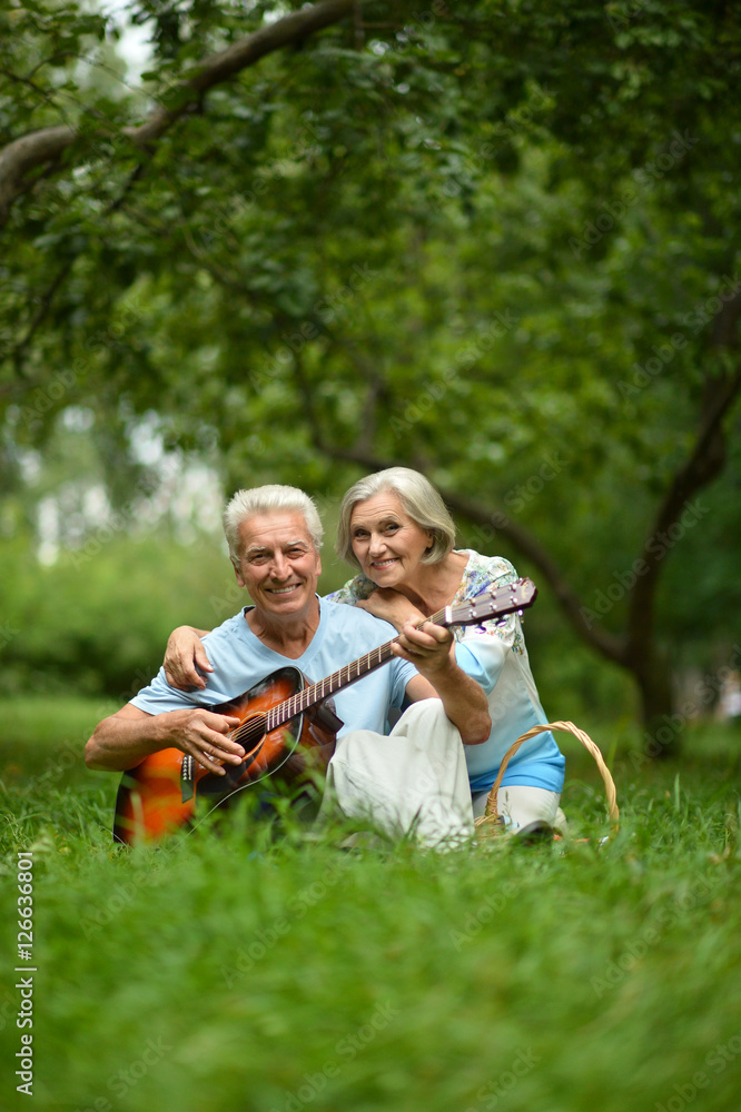 mature couple with guitar   in park