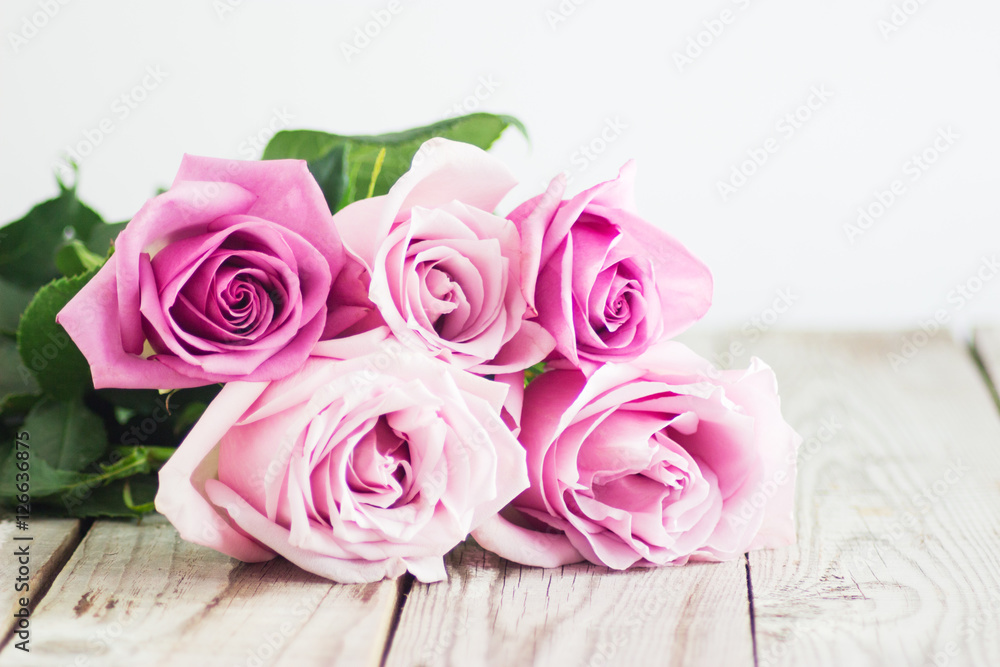 Blurred pink roses on wooden background Blurred pink roses on wooden background