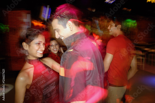 Young people dancing in night club, couple in the foreground