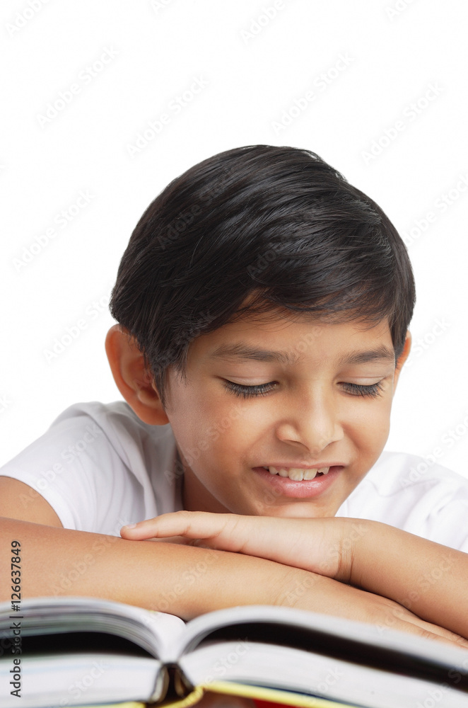 Boy leaning head on hand, looking at book Boy leaning head on hand, looking at book