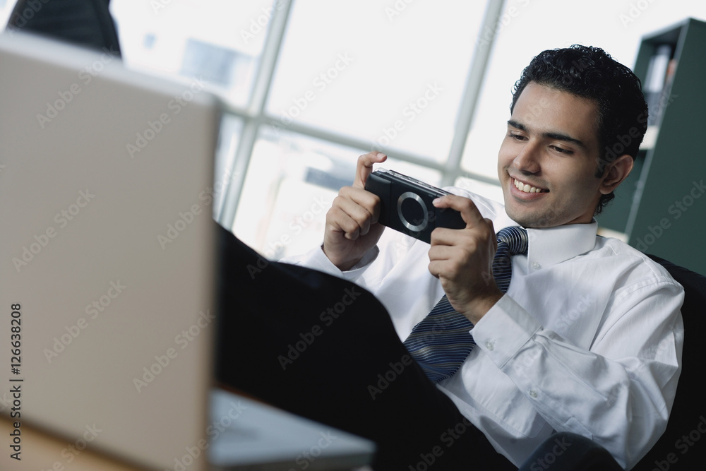 Young businessman playing with Playstation Portable