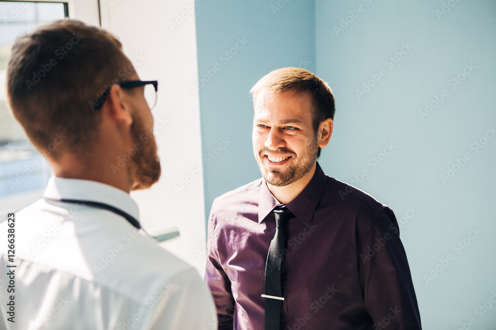 Full length side view of businessmen shaking hands in office building Full length side view of businessmen shaking hands in office building
