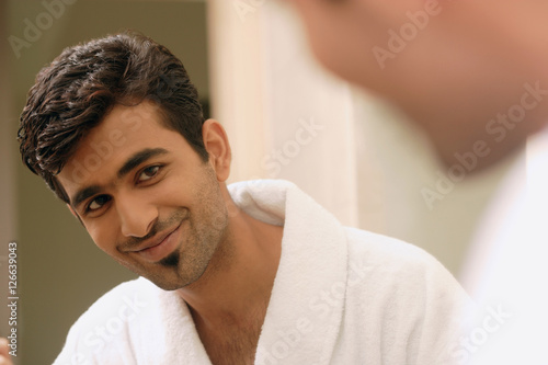 Man looking at his reflection in mirror, smiling