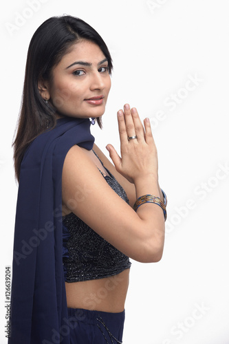 Woman in traditional Indian clothing, hands together, turning to look at camera photo