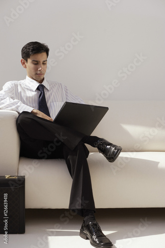 A man sits on a couch with a laptop