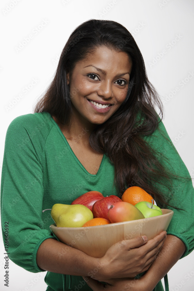 Woman wearing green top holding bowl of fruit Woman wearing green top holding bowl of fruit