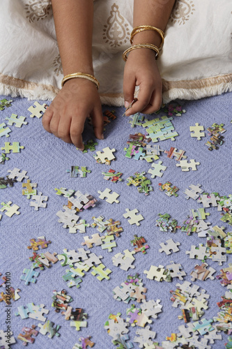 Hands of little girl working on puzzle