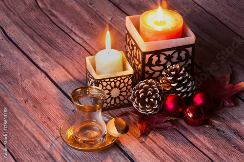 Vaso de té, velas y decoración navideña.