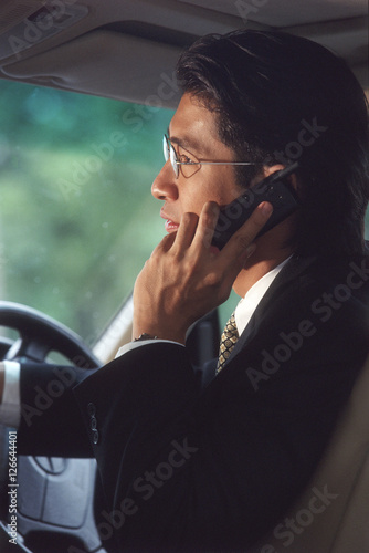 Male executive talking on cellular phone in car, profile