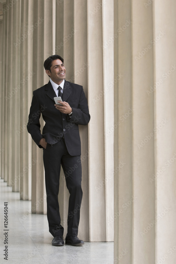Businessman in suit standing in front of columns Businessman in suit standing in front of columns