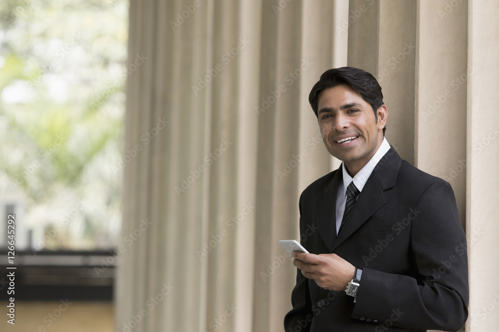 Businessman in suit looking up from mobile phone Businessman in suit looking up from mobile phone