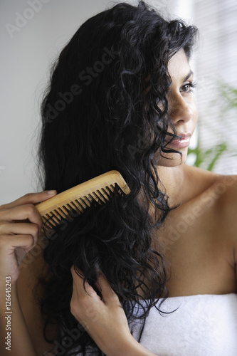 Indian woman with bare shoulders and combing her hair.