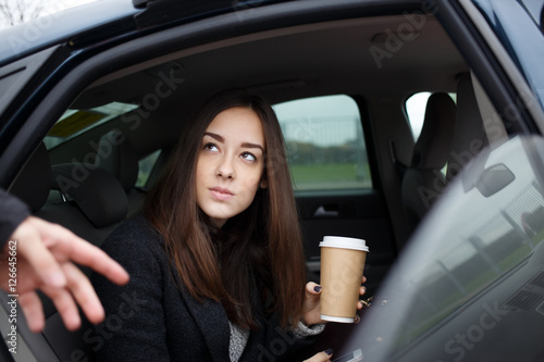 Beautiful young brunette woman going to get out of car