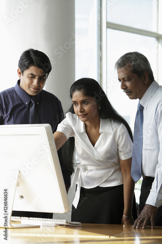 Indian woman looking at a computer with male colleagues